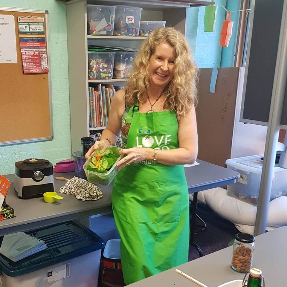 Kerrie wearing a green "Love Food Hate Waste" kitchen apron