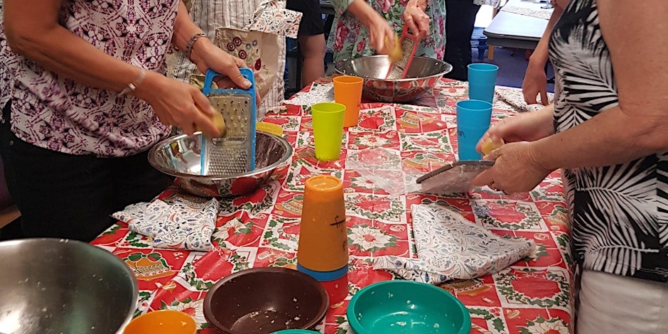 Several persons grating wax on a kitchen table